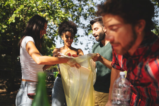 Group of friends committed to the environment - young people happily participate in a clean-up, ensuring their outdoor gathering leaves no trace behind.