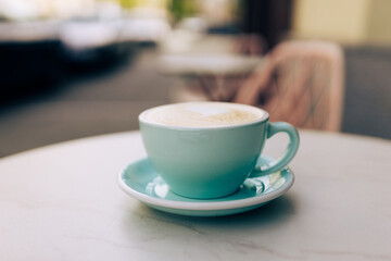 Blue Cup of cappuccino with latte art. Coffee in blue cup on the table in cafe. Coffee break. Close-up.