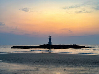 Fototapeta premium A tranquil seascape with a lighthouse silhouette against a vibrant sunset, perfect for themes of travel and nature