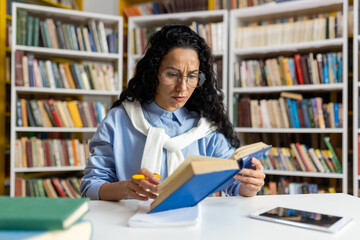 A dedicated student engrossed in reading a book surrounded by a vast collection of literature in a well-stocked library.