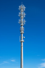 Telecommunication tower pole with signal 5G transmitters against blue sky - 780690734