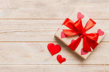 Top view photo of valentine day decorations gift box with red ribbon bow on colored background....