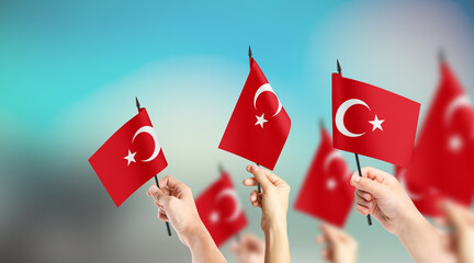 A group of people are holding small flags of Turkey in their hands.
