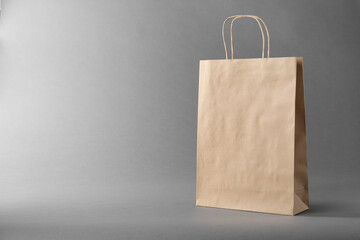 One kraft paper bag on grey background, space for text. Mockup for design