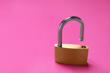 One steel padlock on pink background, closeup. Space for text