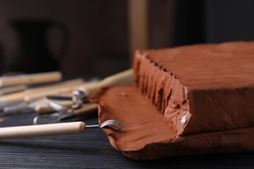Clay and modeling tool on dark gray wooden table in workshop, closeup