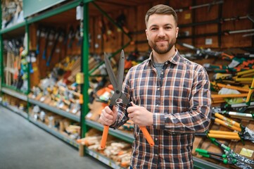 a customer chooses a garden shears for himself in a garden supply store