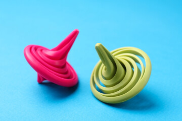 Pink and green spinning tops on light blue background, closeup
