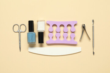 Nail polishes and set of pedicure tools on beige background, flat lay - obrazy, fototapety, plakaty
