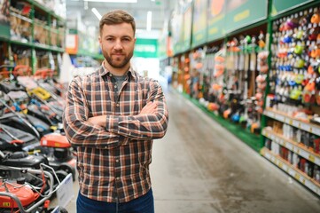 Young man working in hardware store - obrazy, fototapety, plakaty