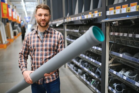 male plumber in a hardware store chooses the sewer pipes, the concept of plumbing work in the house