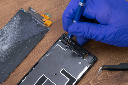A gloved handyman makes a diagnosis of a faulty smartphone, close-up