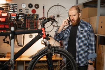 Fototapeta na wymiar Portrait of handyman standing with phone in equipped workshop or garage. DIY