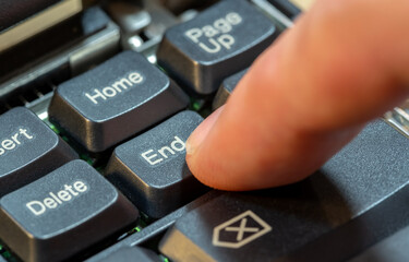 Man pressing the End key on a laptop computer keyboard, finger closeup, one person. Ending an...