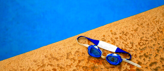 Swimming Goggles Next to Pool with Blue Water - 780705534