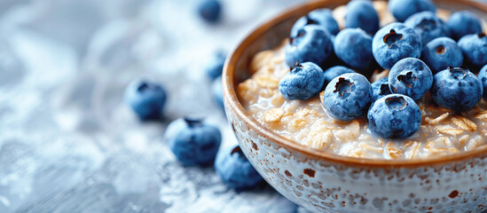 Banner, oatmeal with milk and blueberries dish on a white marble table, copy space. Healthy breakfast concept. - obrazy, fototapety, plakaty