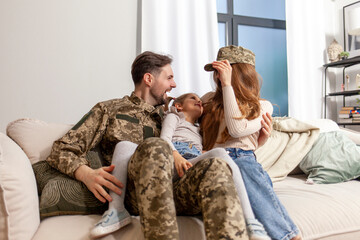 Ukrainian military man in camouflage uniform hugs his family at home and smiles, a happy soldier of...