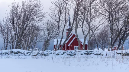 Fototapeten rote Kirche in Flakstad ist schneebedeckt, kahle Bäume im Vordergrund © Johannes