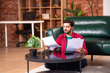 Indian man is busy in accounting at home sitting in living room