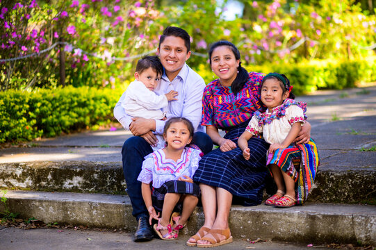 A happy and united family takes a portrait sitting in a park in their city.