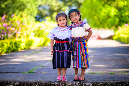 A pair of sisters are photographed in the middle of a city park.