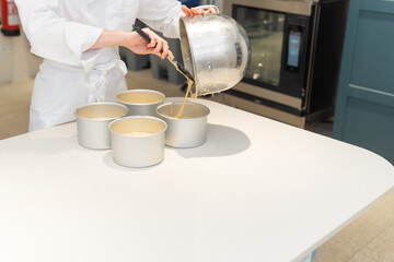 Close-up photograph of Pastry Chef pouring cake batter into molds with a pastry tongue. copy space.Close-up