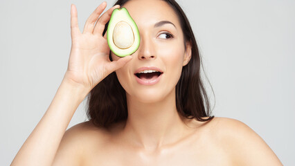 Young beautiful woman holding half an avocado