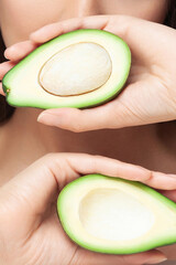 Close-up of avocado cut in half in woman's hands