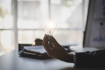 Businessman hand holding light bulb and idea.