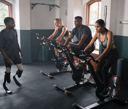 Group of individuals doing indoor cycling on stationary bicycles in the gym