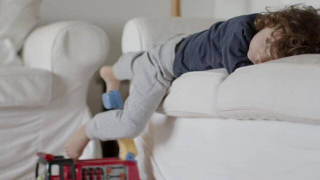 Cute boy lying on a couch, in a modern living room