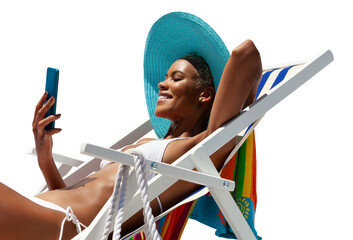 Happy young woman is sunbathing on a beach deck chair, uses mobile phone, isolated on white background, concept of a summer beach holiday, online shopping, booking travel, and resort accommodations