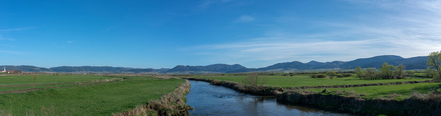 Panorama shot, dirty curving Olt river at springtime in Transylvania, Romania.