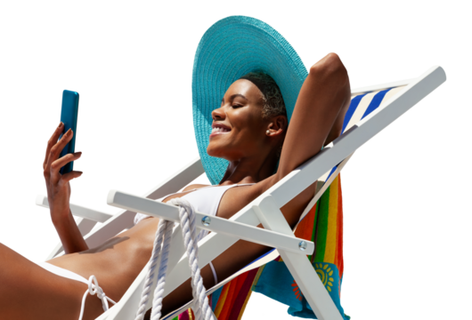 Happy young woman is sunbathing on a beach deck chair, uses mobile phone, isolated on white background, concept of a summer beach holiday, online shopping, booking travel, and resort accommodations