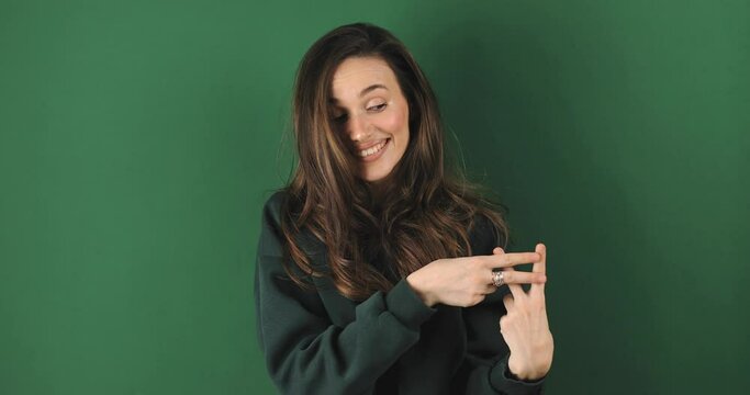 Hashtag. Woman showing hashtag symbol with fingers hands, likes tagged message, popular viral social media content, sign to follow internet online trends. Girl isolated on green studio background.