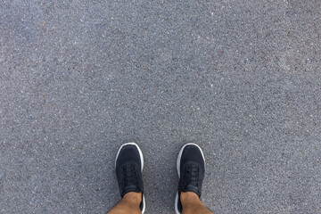 Fitness and healthy lifestyle concept. Man looking running sneakerson a asphalt road. Top view and...