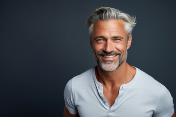 A man with a white shirt and gray hair is smiling
