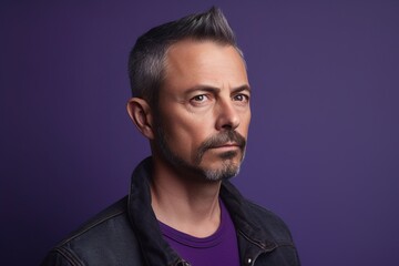 Obraz premium A man with a beard and gray hair is wearing a black jacket and a purple shirt