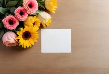 a bouquet of flowers and a blank card on a wooden table