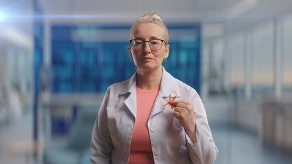 Middle-aged doctor in medical suit showing red ribbon, HIV and AIDS awareness