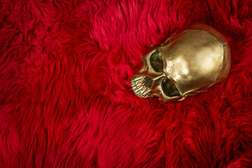 A golden skull lying on a fluffy cushion of red fur