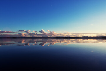 Fototapeta na wymiar Clouds in the distance mirrored in the deep blue , calm water of Fern Ridge Reservoir in Oregon.