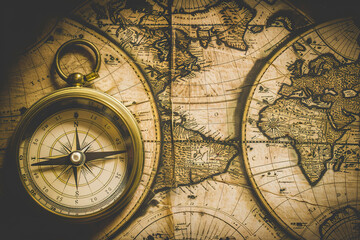 A vintage map of the world with an old-fashioned compass placed on top