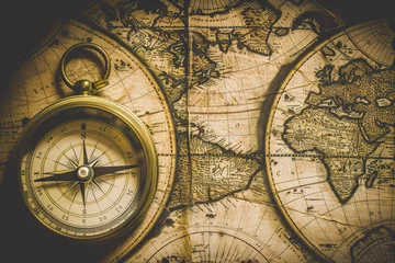 Fotobehang A vintage map of the world with an old-fashioned compass placed on top © Sergio