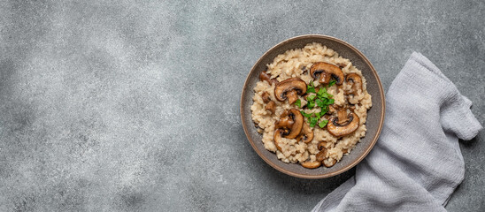 Risotto with mushrooms on a gray rustic background. Top view, flat lay, copy space. Banner