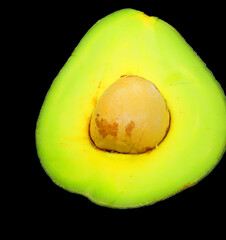 green avocado with a large seed on black background