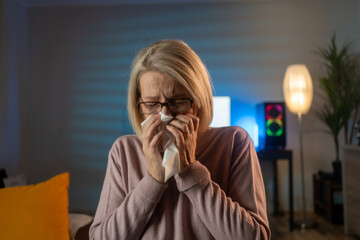 Woman blowing nose at home.