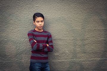 Isolated, depressed teenage boy standing alone against muted backdrop.