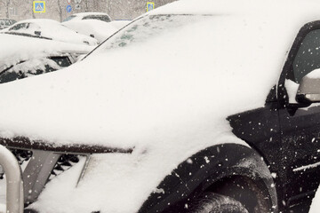 A car covered with snow stands in the parking lot