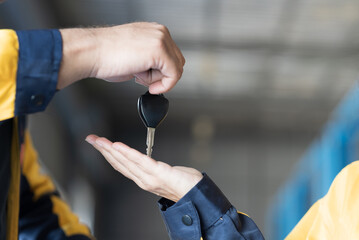 Hands of mechanics holding key of car at auto car repair service. Car service and Maintenance...